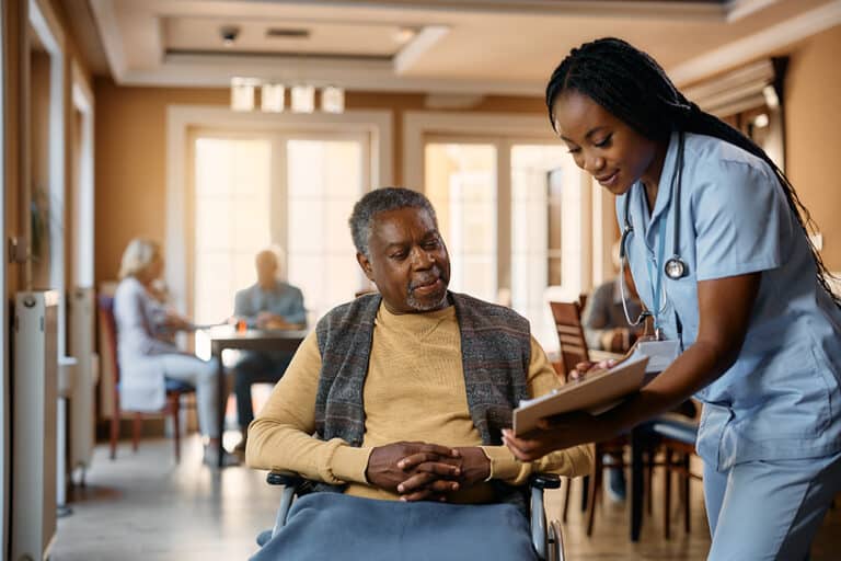 Nurse holding a clipboard talking with an elderly man